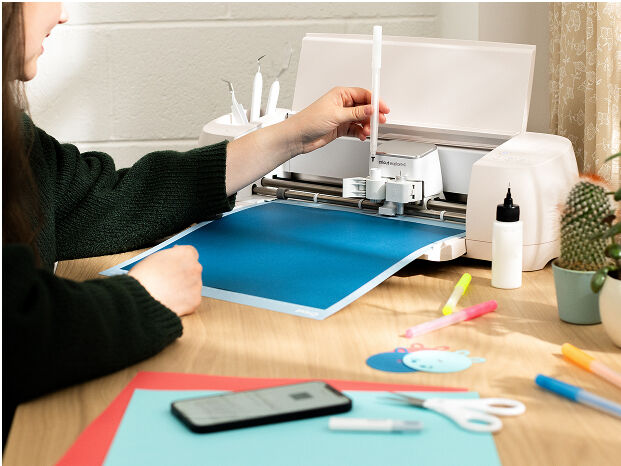 Woman's hand holding a smart phone with a personalized project template pulled up using Cricut's Design Space app